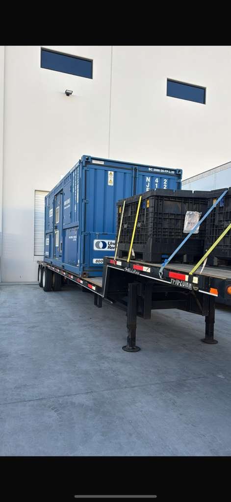 Flatbed trailer loaded with a shipping container and secured crates